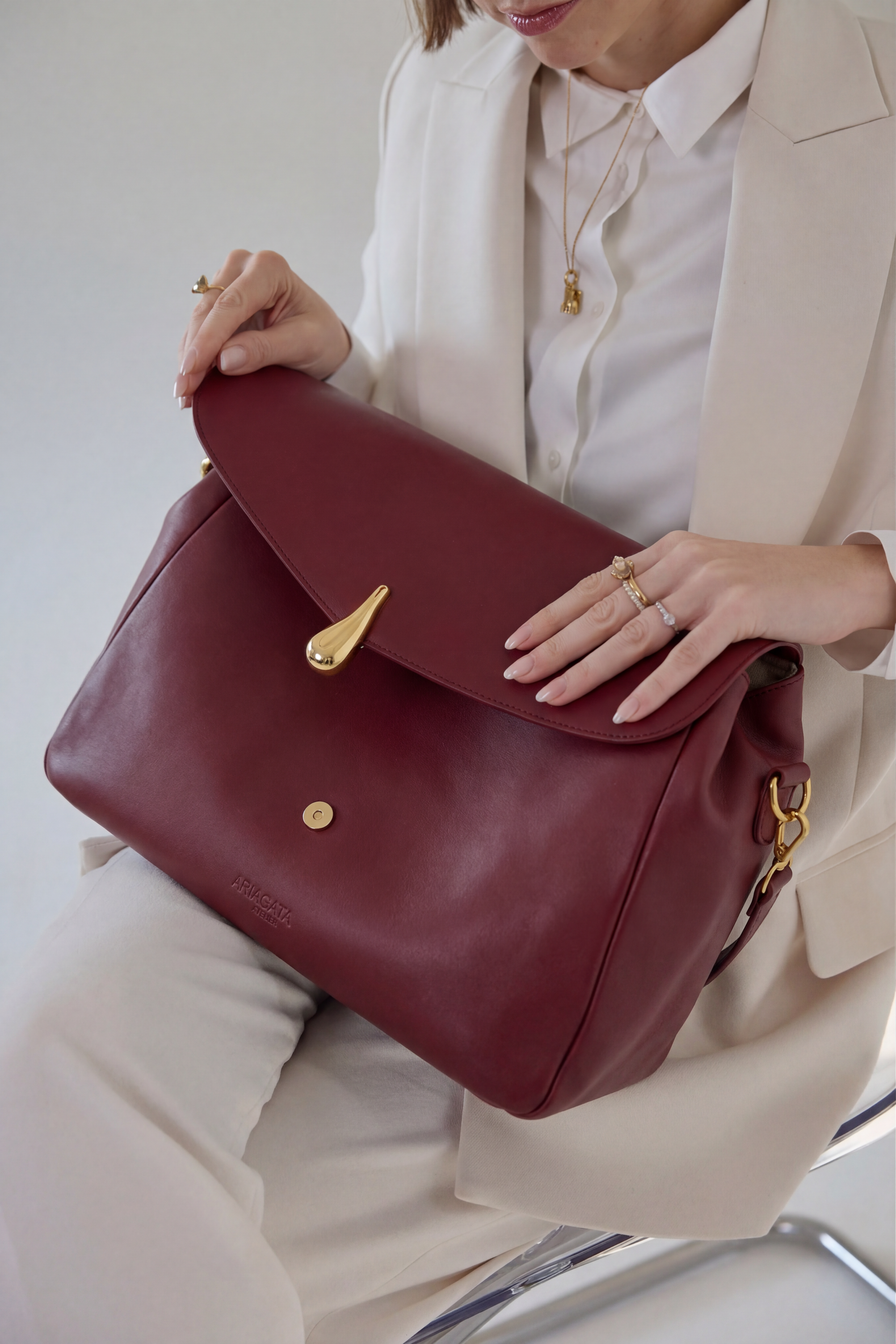 Bordeaux red designer laptop bag worn by a woman in a business setting